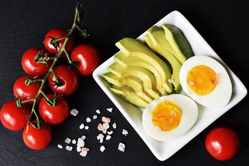 Comida saludable: rodajas de aguacate, tomates y huevo.