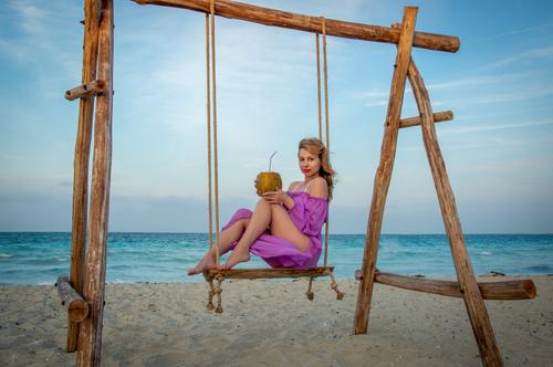Mulher com um coco num baloiço de praia