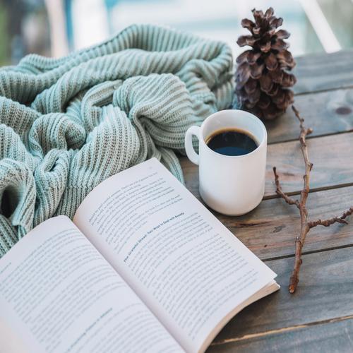 Book near a cup and blanket